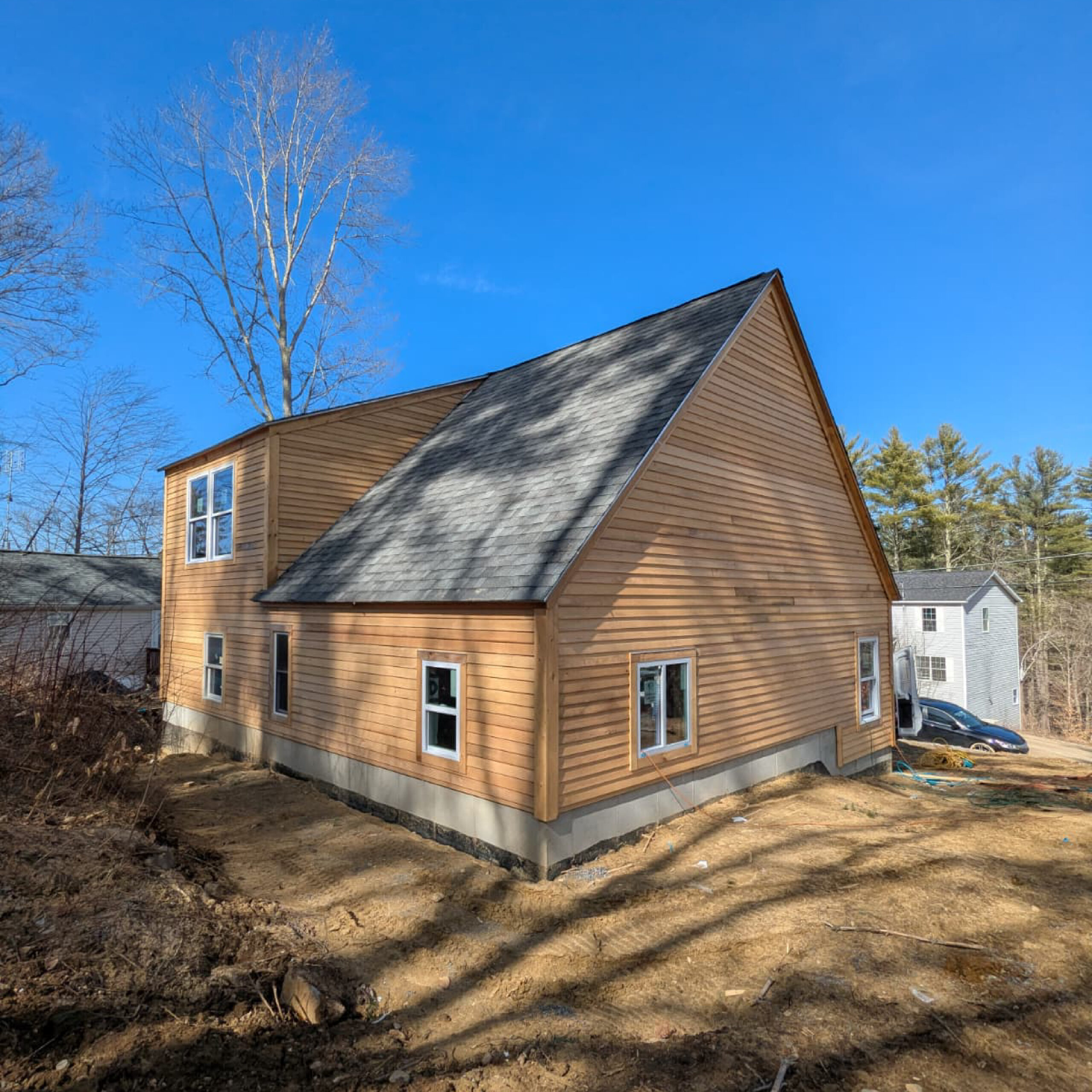 Side exterior of a modern wood-clad residential home by Family Realty Holdings