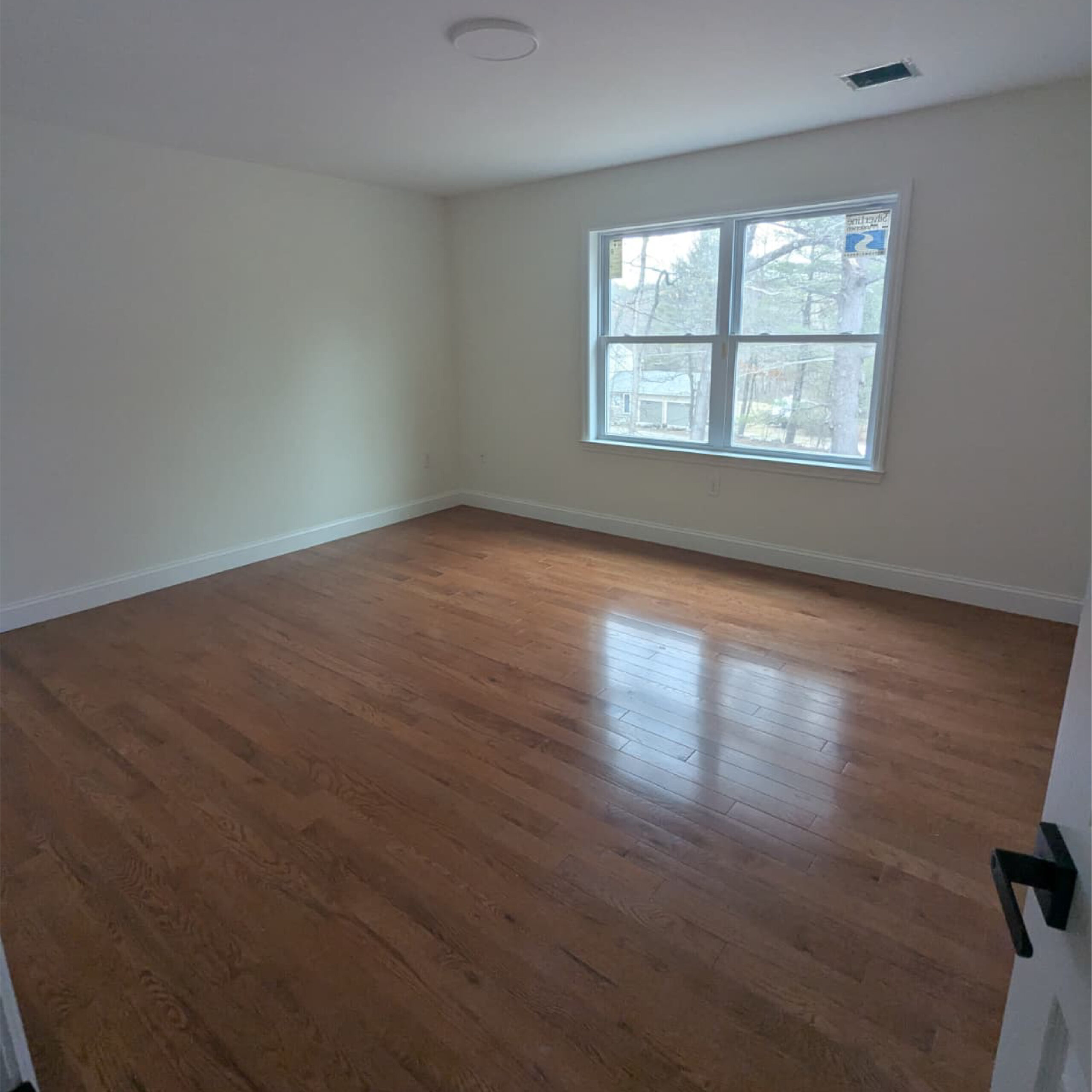 Empty bedroom interior with hardwood floors by Family Realty Holdings