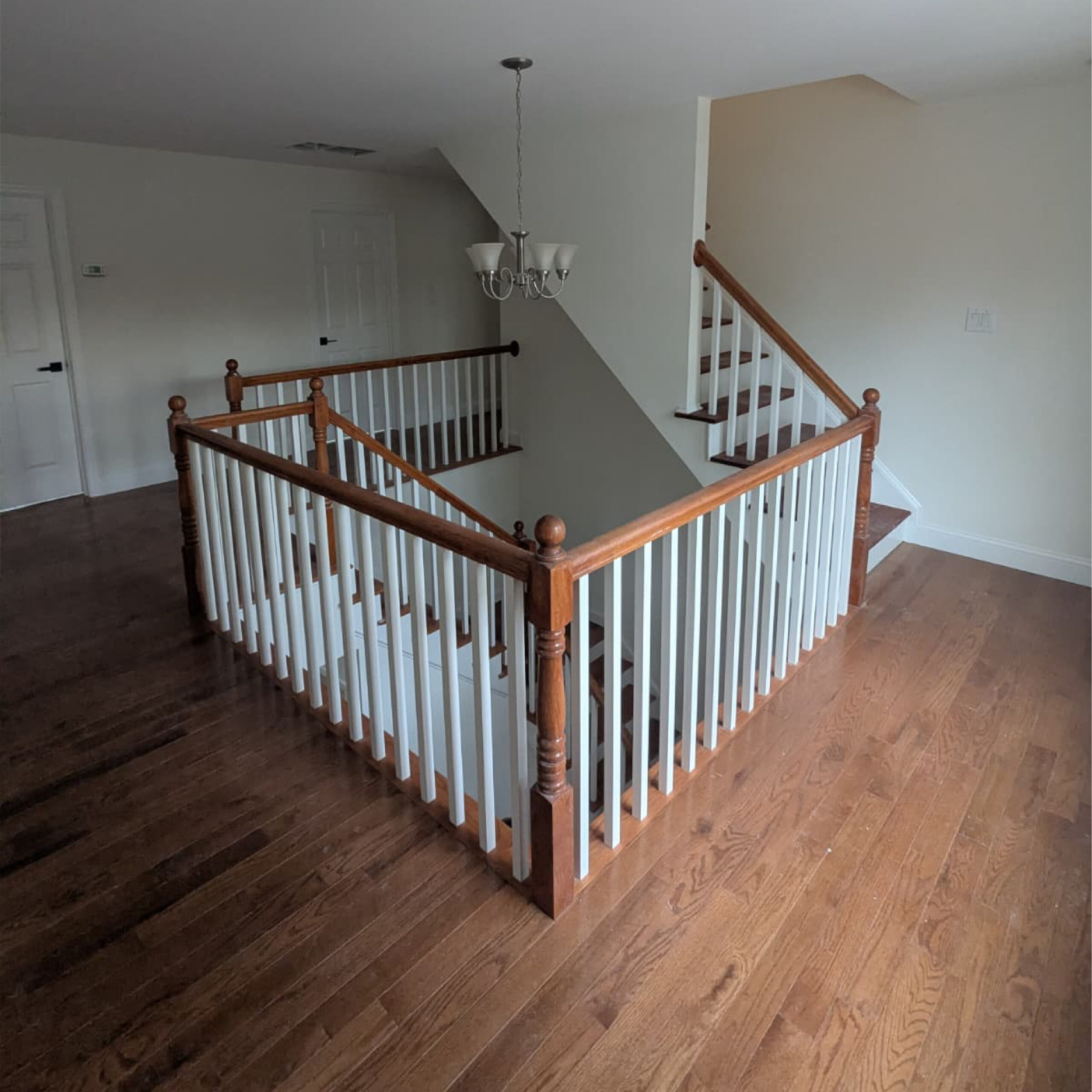 Interior staircase with hardwood flooring designed by Family Realty Holdings